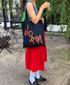 WORM DENIM TOTE BAG BEING WORN BY WOMAN IN RED DRESS