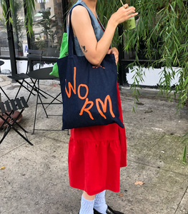 WORM DENIM TOTE BAG BEING WORN BY WOMAN IN RED DRESS